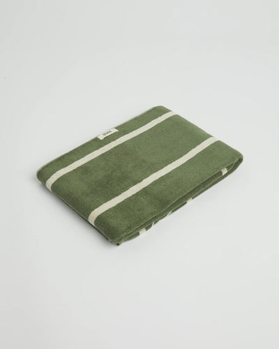 Green towel with white stripes on a light gray background