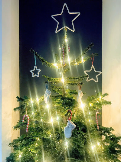 Decorated Christmas tree with lights and star-shaped ornaments against a dark background