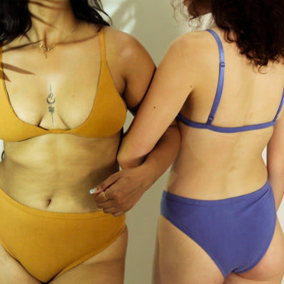 Two women wearing yellow and blue bikinis standing close to each other.