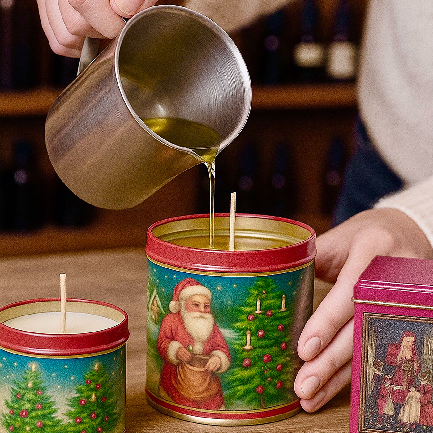 Person pouring liquid into a Christmas-themed candle tin on a wooden surface.