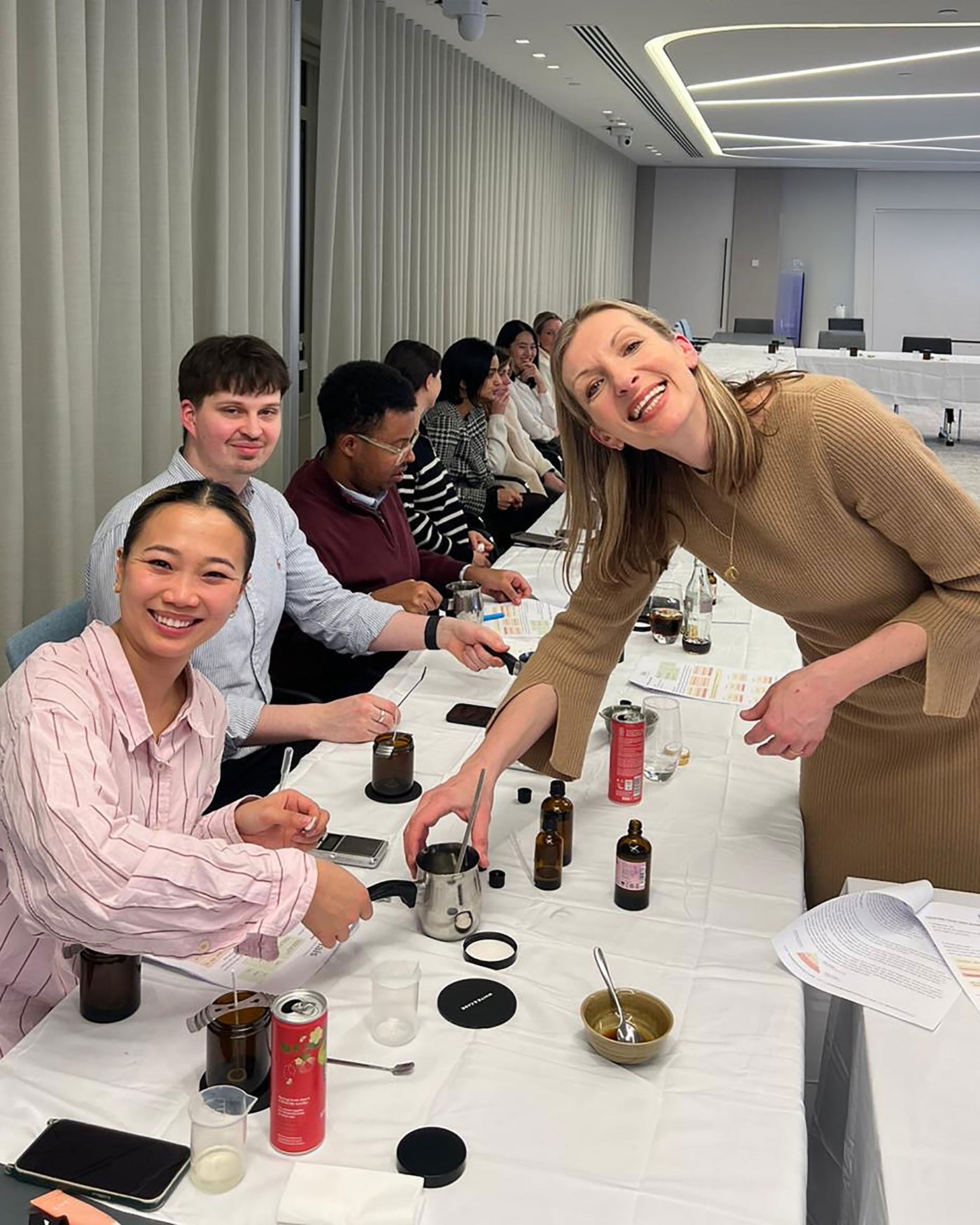 Group of people at a conference table with various items on it, including bottles and a can.