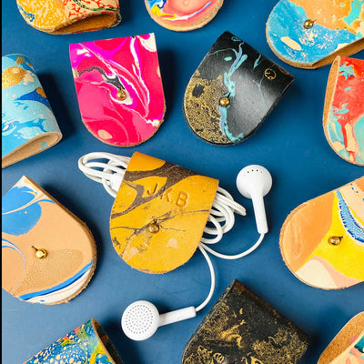Colorful marble-patterned cases with earphones on a blue background