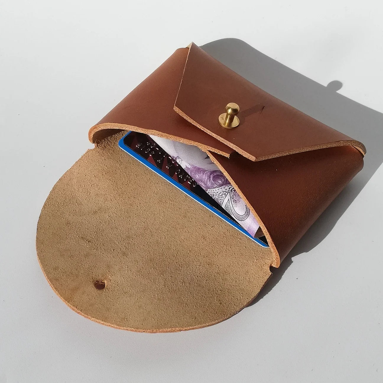 Brown leather case with a gold button on a light gray background