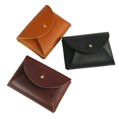 Three leather pouches in brown, black, and red on a white background