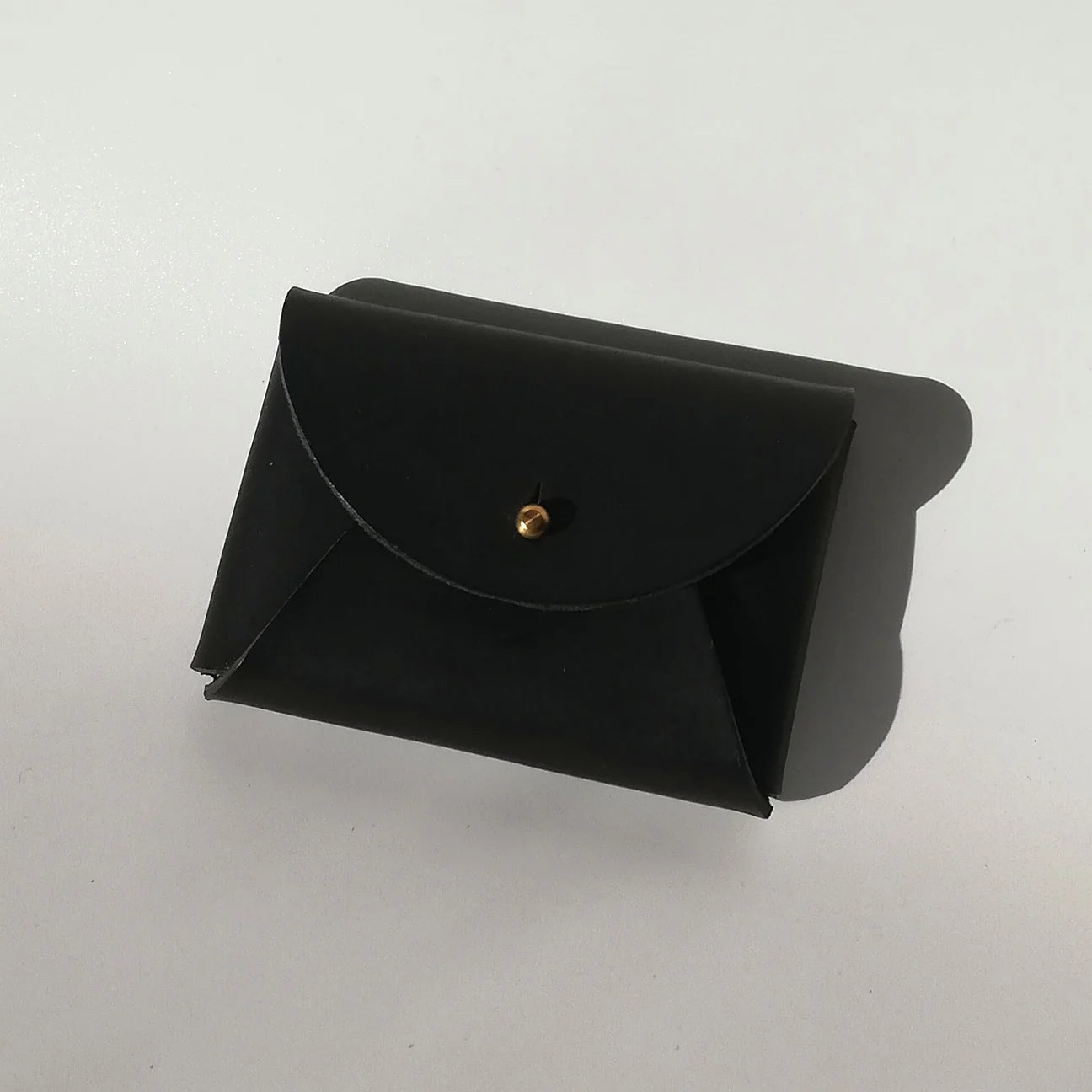 Black leather pouch with a gold button on a white background