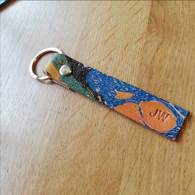Colorful leather keychain with 'JW' initials on a wooden surface
