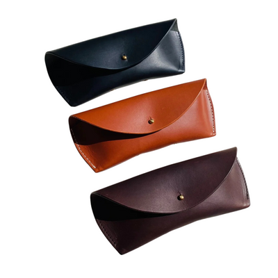 Three leather eyeglass cases in black, brown, and dark brown on a white background