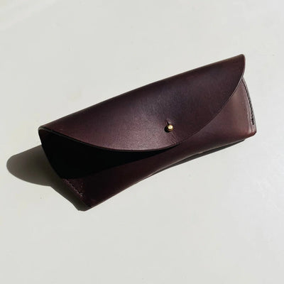 Brown leather sunglasses case on a light gray background