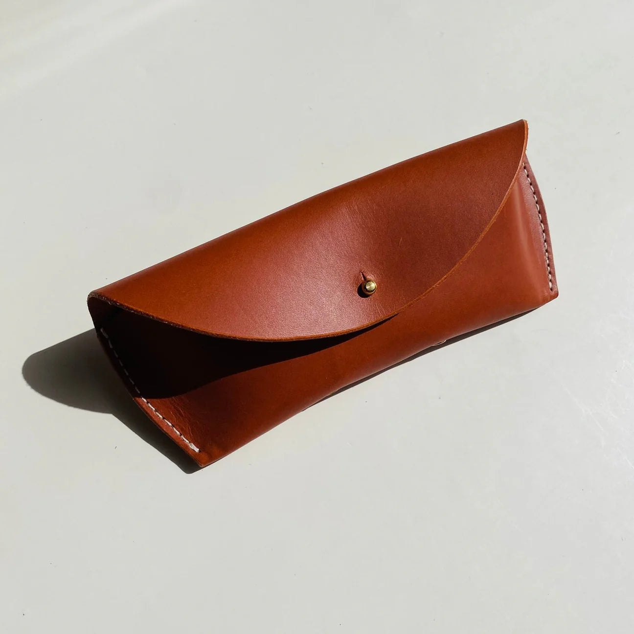 Brown leather case with a gold button on a light gray background