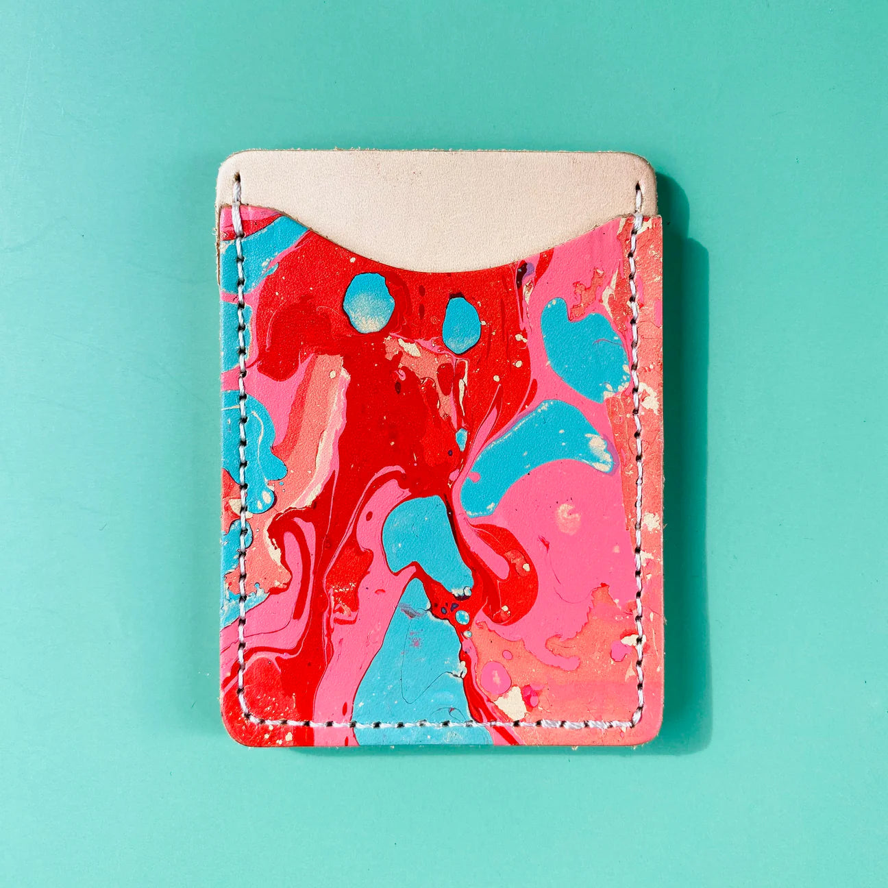 Marbled red, blue, and pink cardholder on a teal background