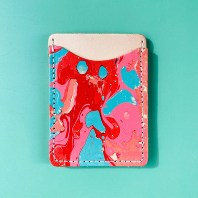 Marbled red, blue, and pink cardholder on a teal background